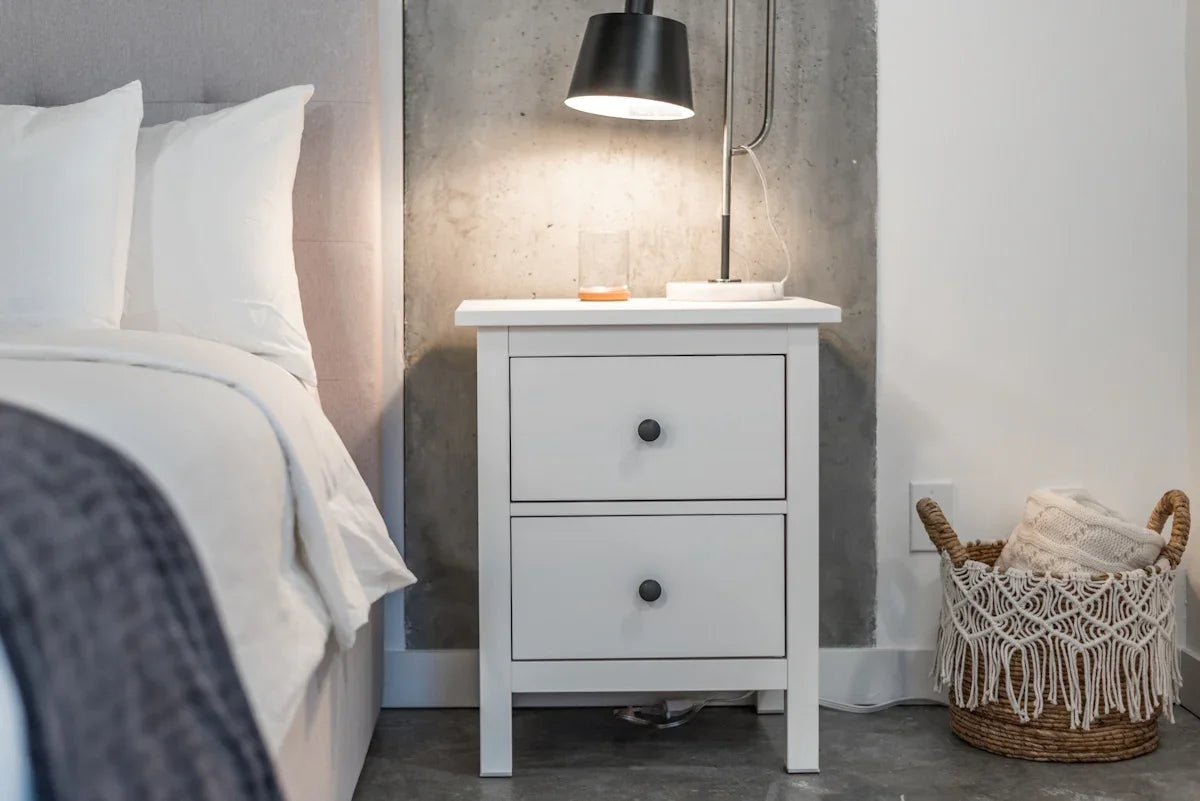 a bedroom with a bed and a nightstand with a lamp on top of it