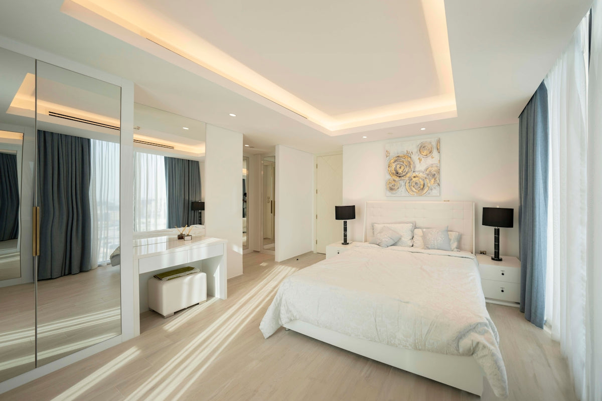A bedroom with a large white bed sitting next to a window