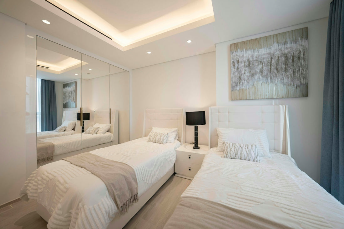 A bedroom with two beds and a mirror