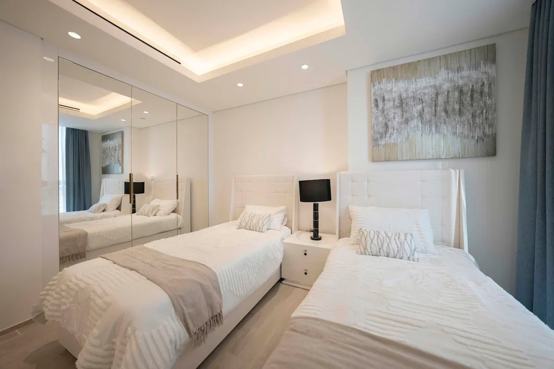 A bedroom with two beds and a mirror