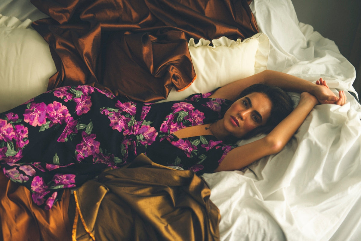 A woman laying on a bed in a dress