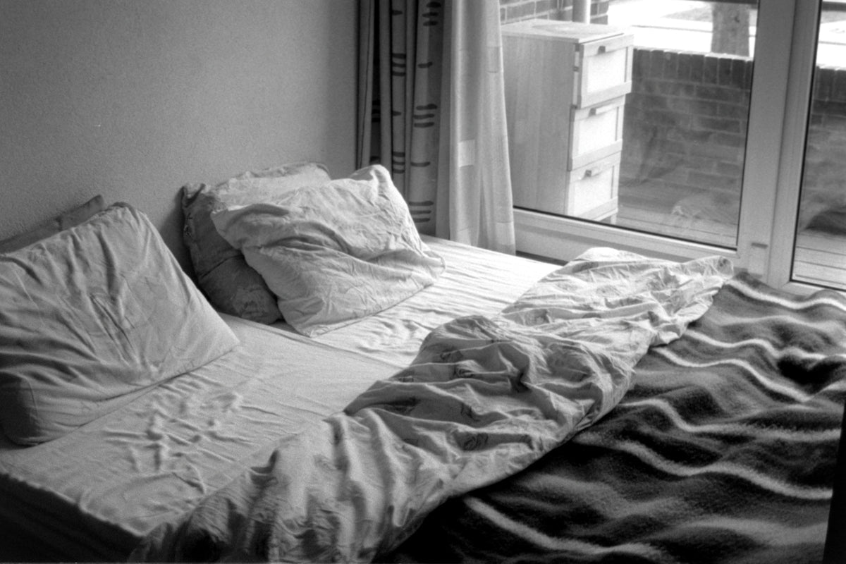 A bed is unmade near a window