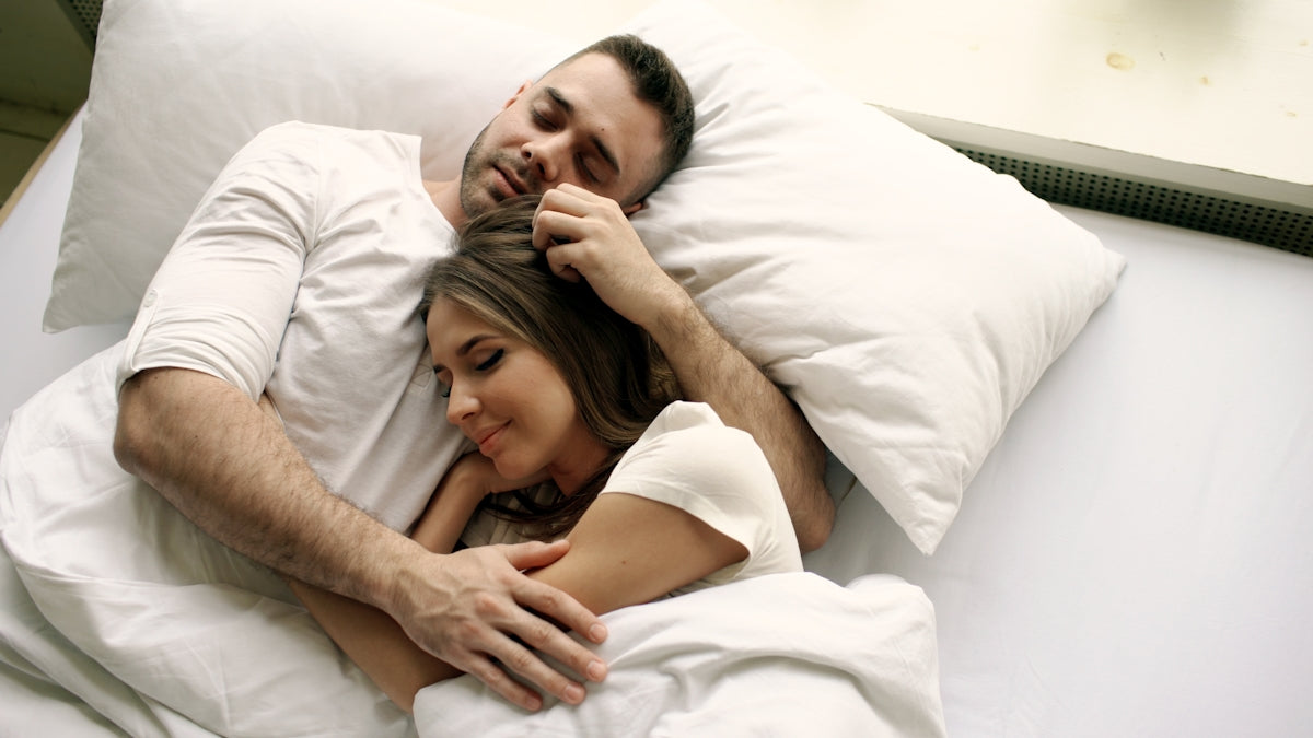 Couple sleeping peacefully in bed together.