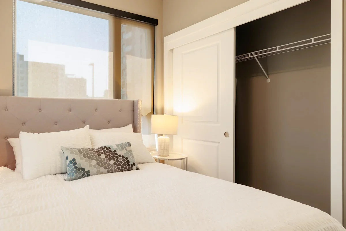 Bedroom with tufted headboard and open closet.