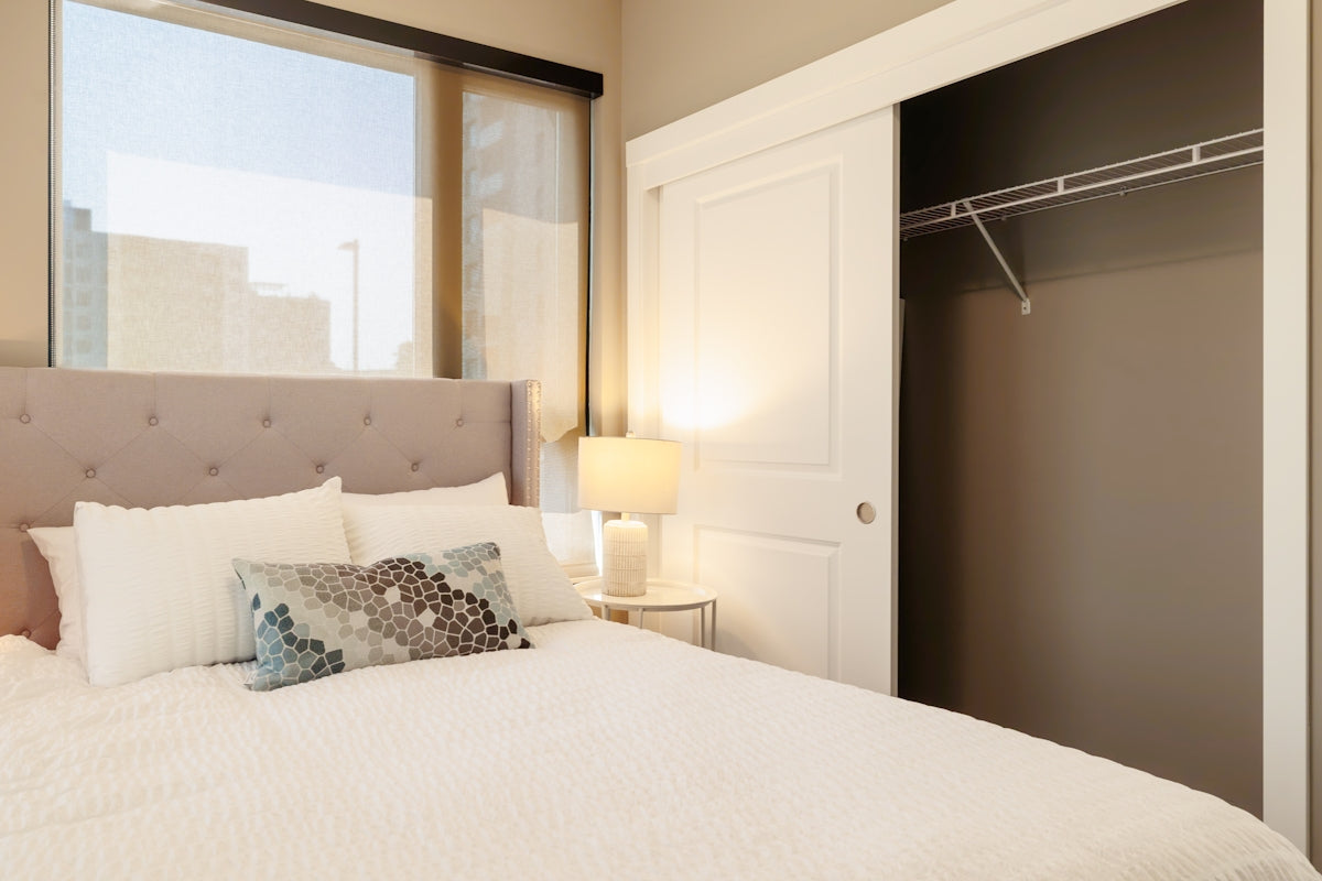 Bedroom with tufted headboard and open closet.