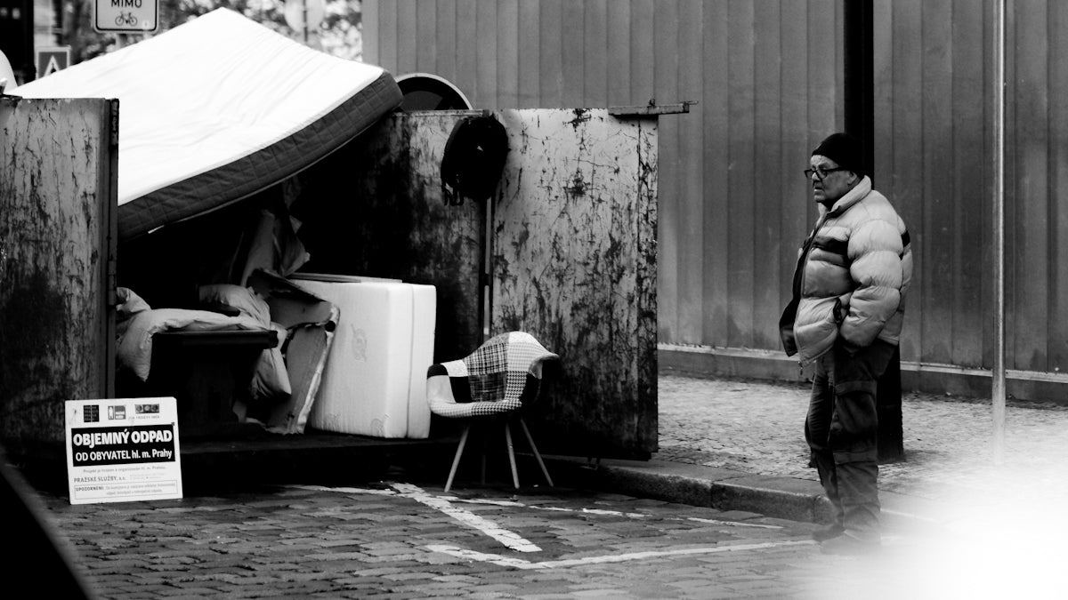 Man stands near makeshift shelter with belongings.