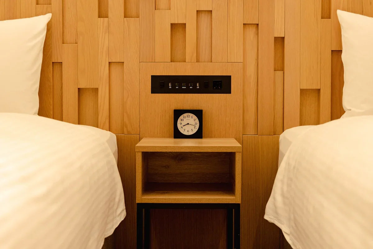 Two beds with a nightstand and clock between them.