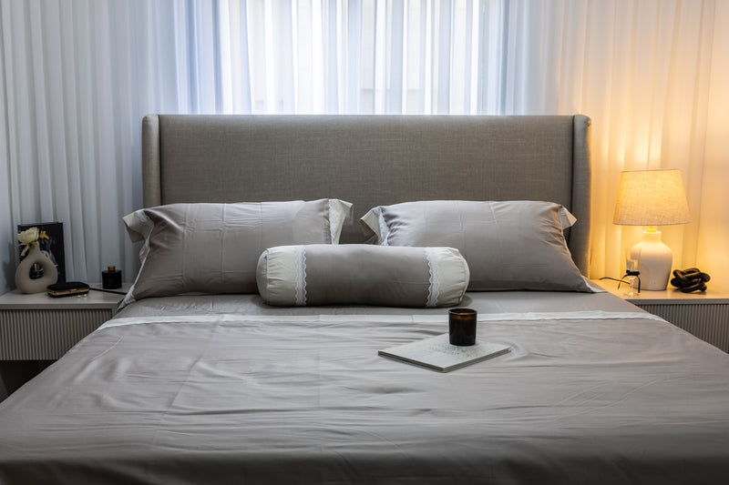 A neatly made bed with pillows and a lamp.