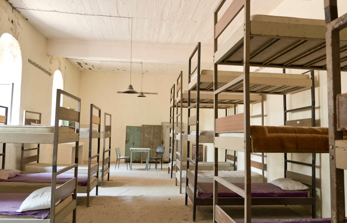 Bunk beds fill a dimly lit dormitory room