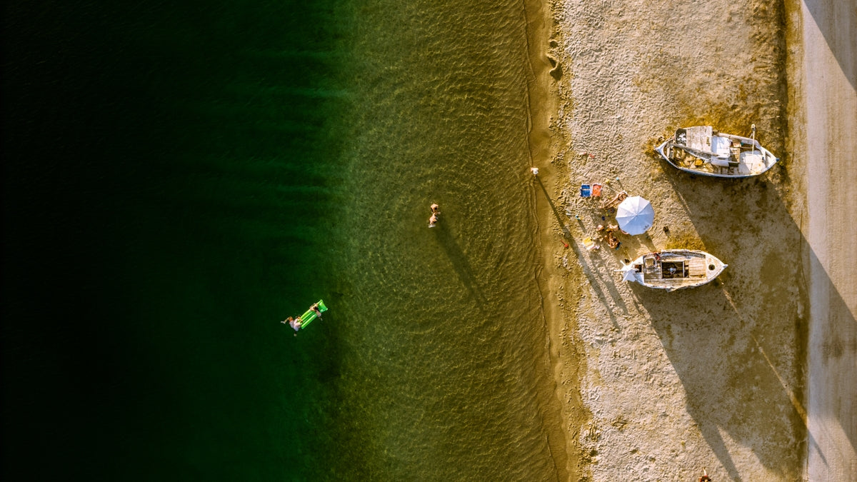 Aerial view of people and boats on a sunny beach.