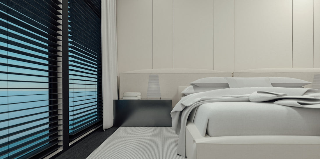Modern bedroom with neatly made white bed and blinds.