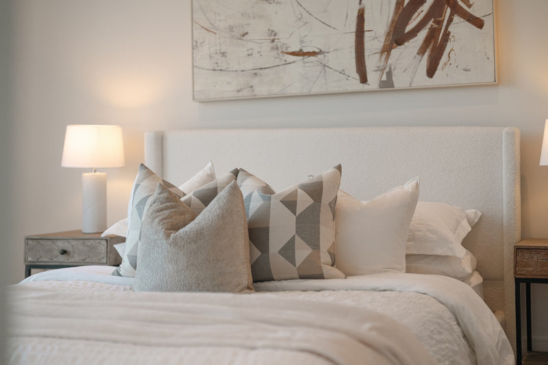 A neatly made bed with decorative pillows and artwork.