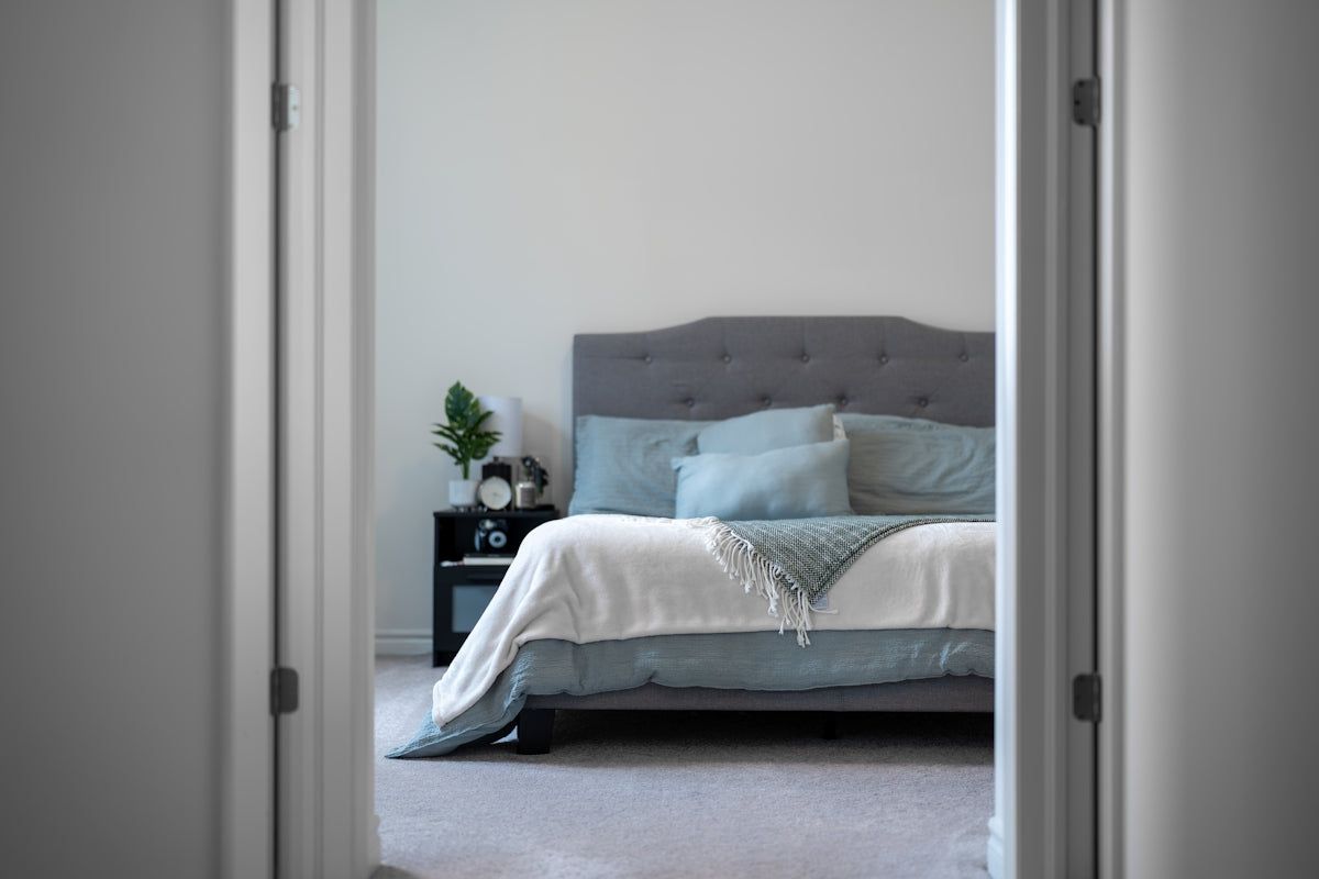 A neatly made bed with blue pillows and white linens.