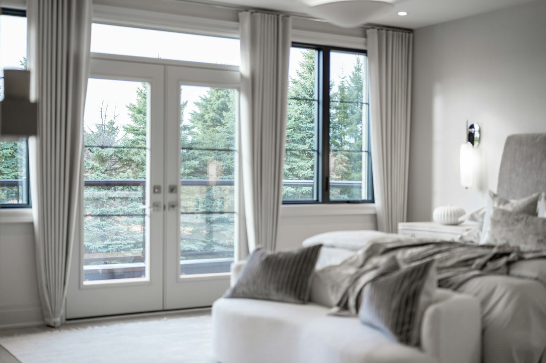 Modern bedroom with large windows overlooking green trees