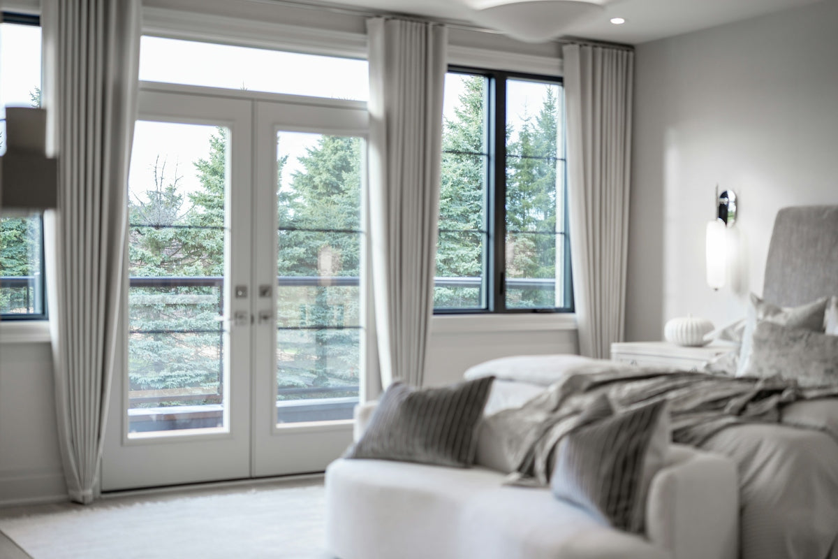Modern bedroom with large windows overlooking green trees