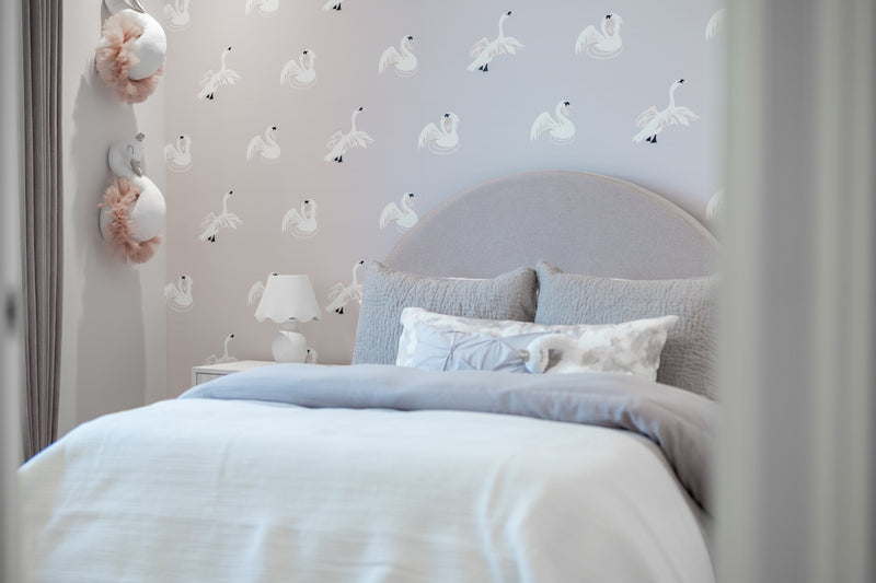 A cozy bedroom with swan-patterned wallpaper and a plush bed.