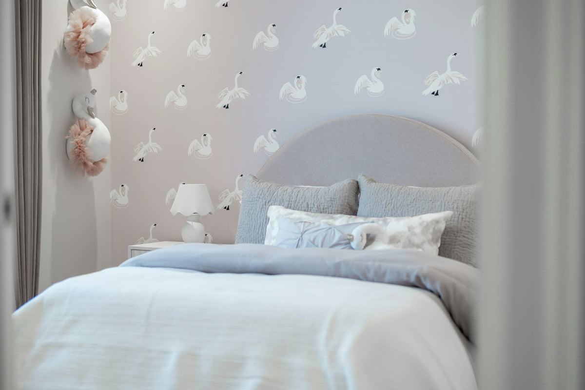 A cozy bedroom with swan-patterned wallpaper and a plush bed