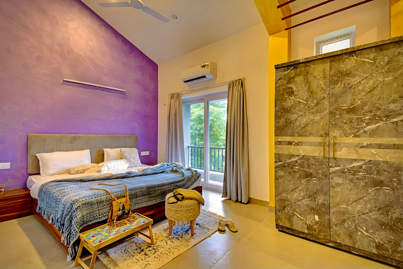 Stylish bedroom with large bed, purple accent wall, and balcony.