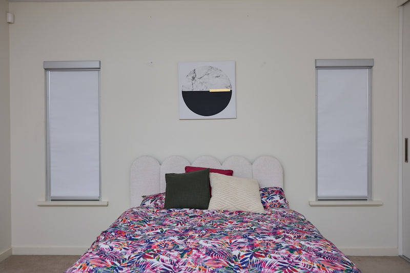 A bedroom with a bed, floral duvet, and abstract art.