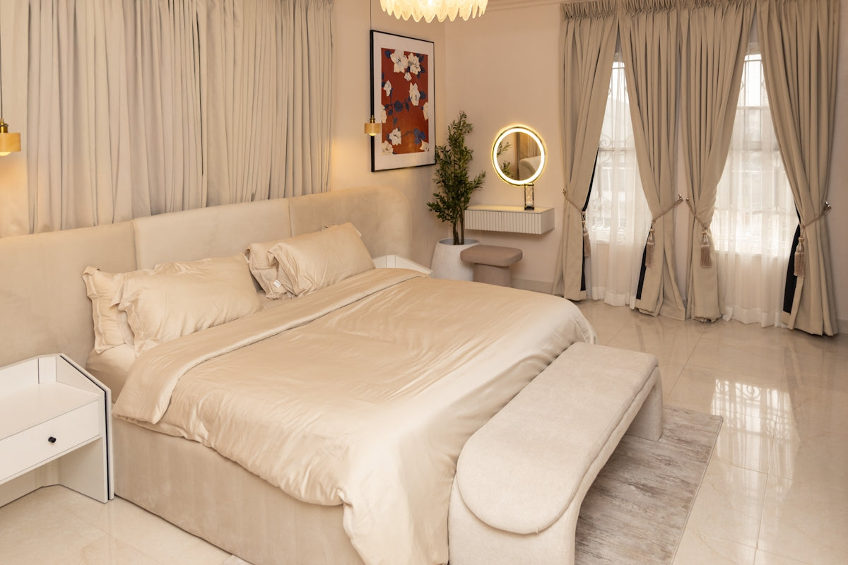 A luxurious cream-colored bedroom with a large bed and vanity