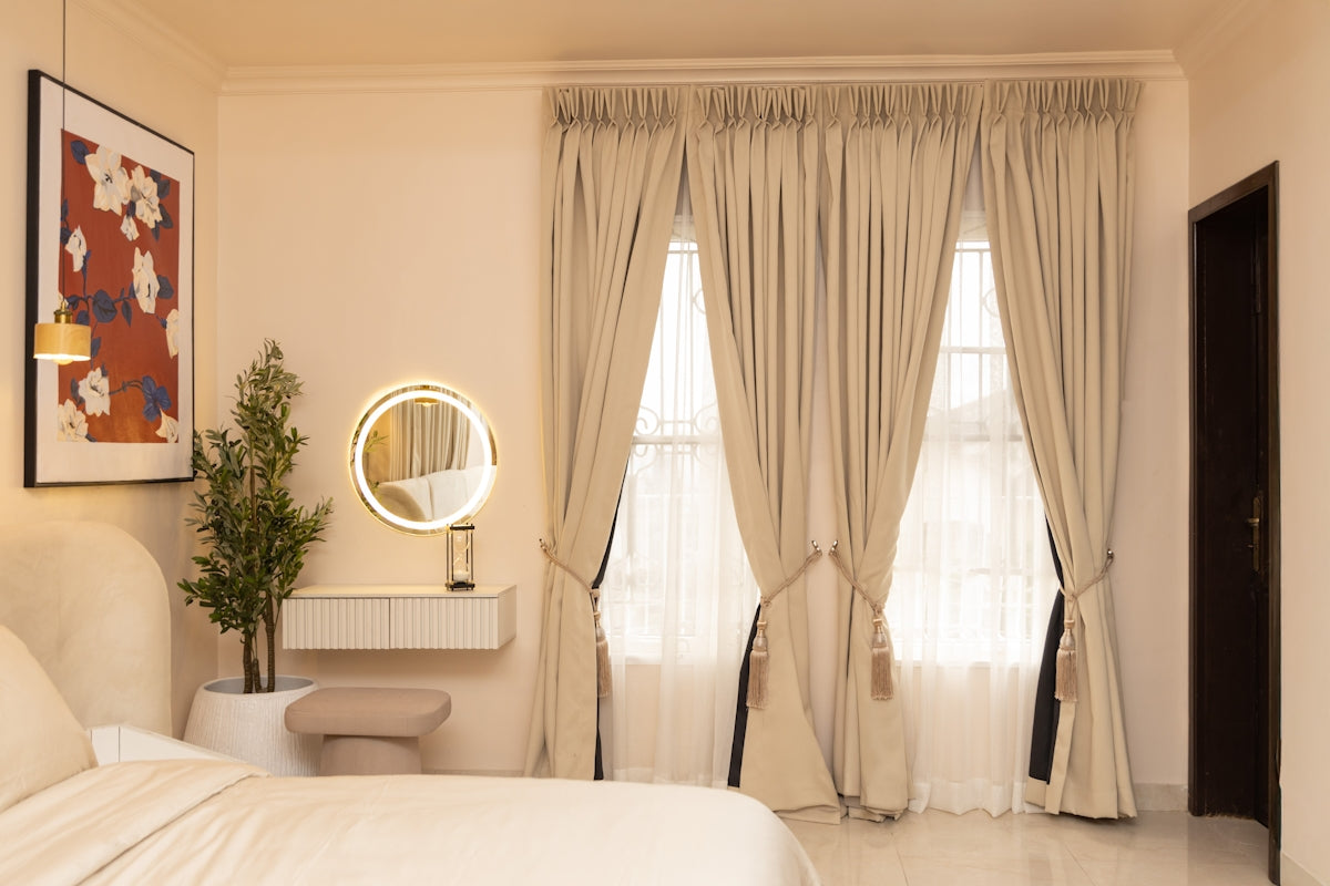 A modern bedroom with a bed, vanity, and long curtains.