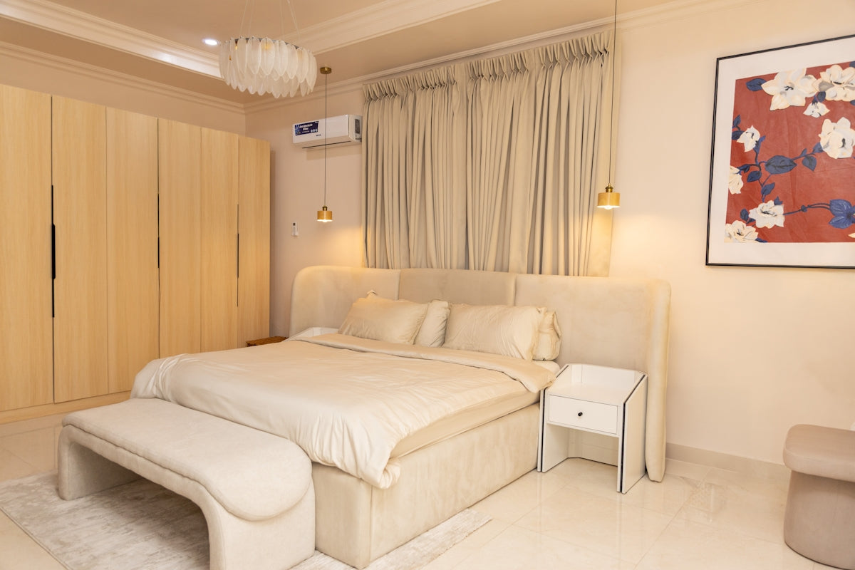 Elegant bedroom featuring a large bed, bench, and neutral decor.