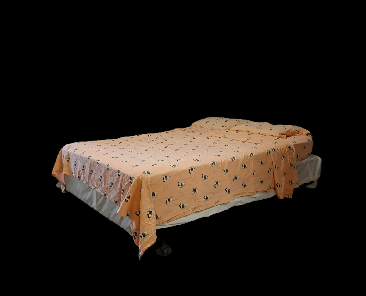 A bed with peach colored sheets featuring a small panda pattern against black