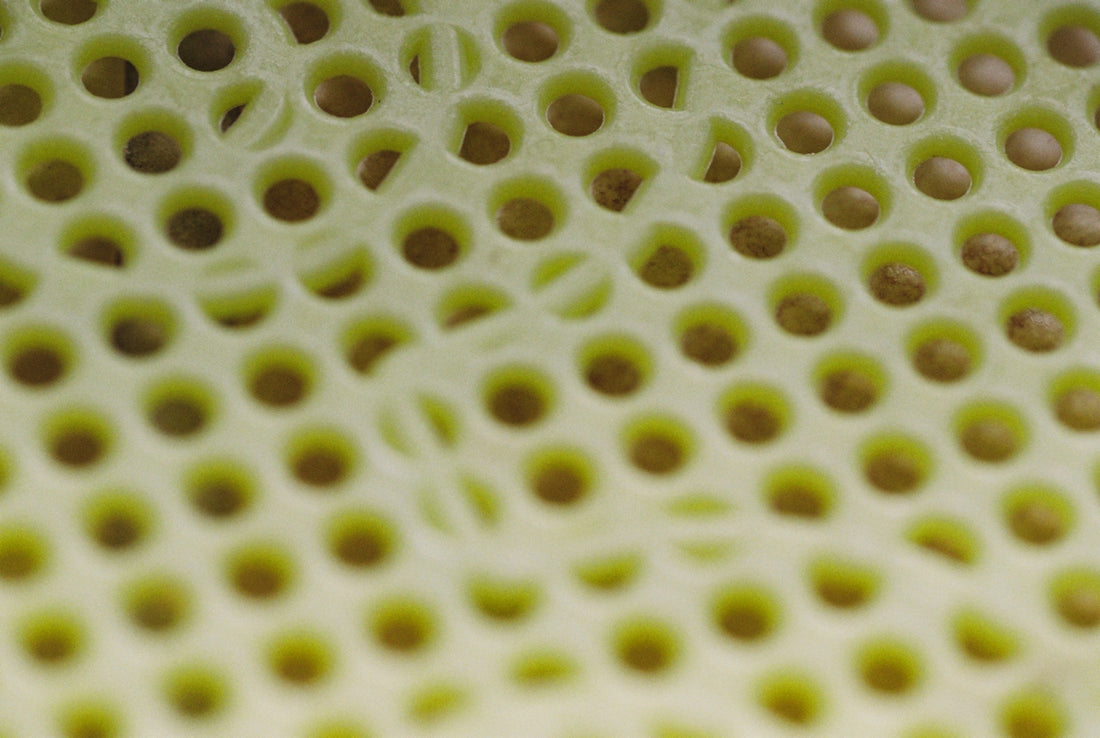 Rows of small round holes in a pale green perforated surface