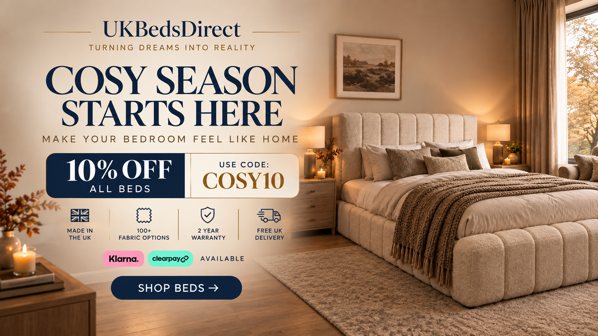 Promotional bedroom scene for UK Beds Direct showing a large upholstered bed with beige bedding and a tufted headboard in a warm, styled bedroom. Large sale text on the left reads 'Cosy Season Starts Here' with discount details and a 'Shop Beds' button.