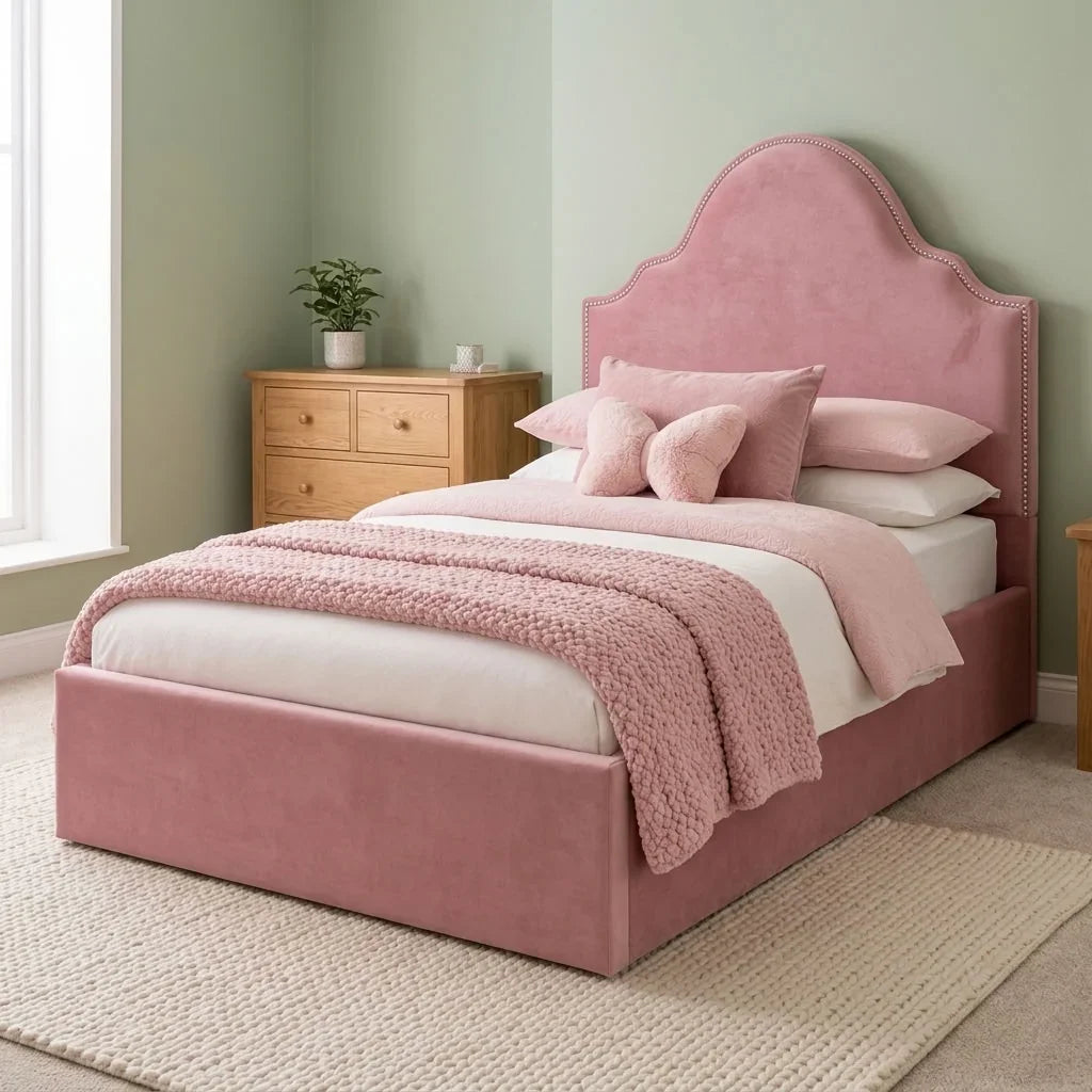 A dusty pink upholstered bed with a matching headboard and footboard, styled with white bedding, pink pillows, and a textured pink throw blanket in a bedroom setting.